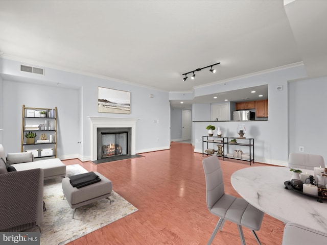 living room with light wood-type flooring, rail lighting, and ornamental molding