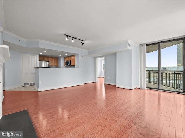 unfurnished living room with ornamental molding, track lighting, light hardwood / wood-style floors, and floor to ceiling windows