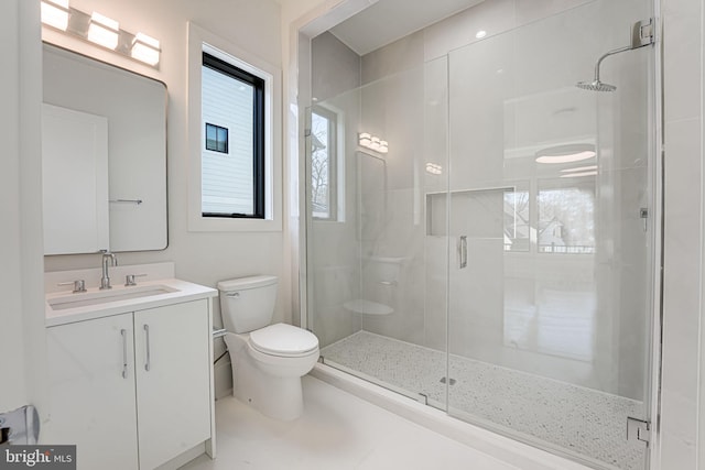 bathroom featuring vanity, a shower with door, and toilet