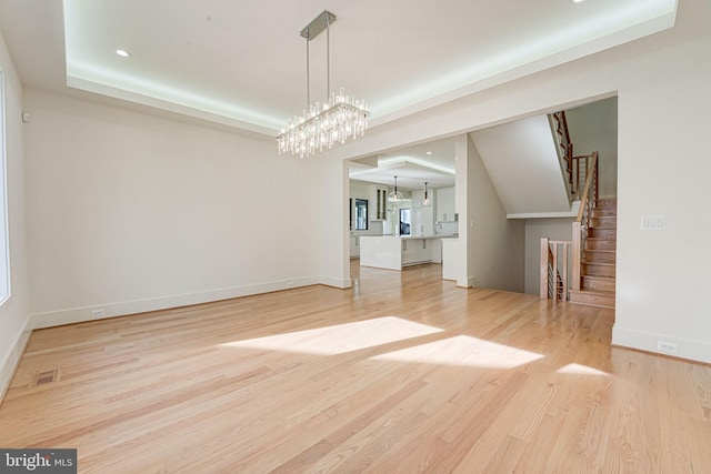 unfurnished living room with an inviting chandelier and light wood-type flooring