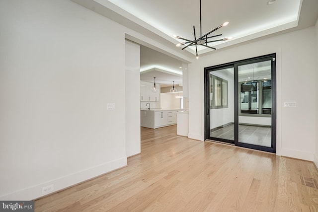 empty room featuring a notable chandelier and light hardwood / wood-style flooring