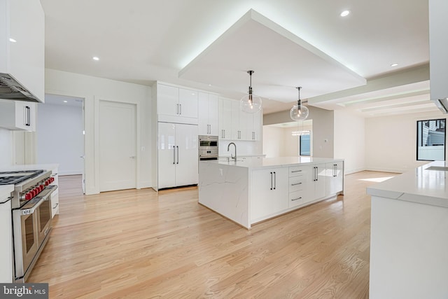 kitchen featuring sink, white cabinetry, a center island with sink, high quality appliances, and pendant lighting