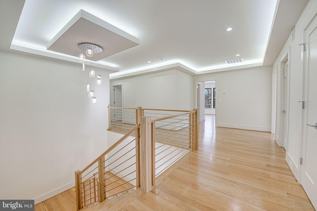 hallway with a raised ceiling and light hardwood / wood-style flooring