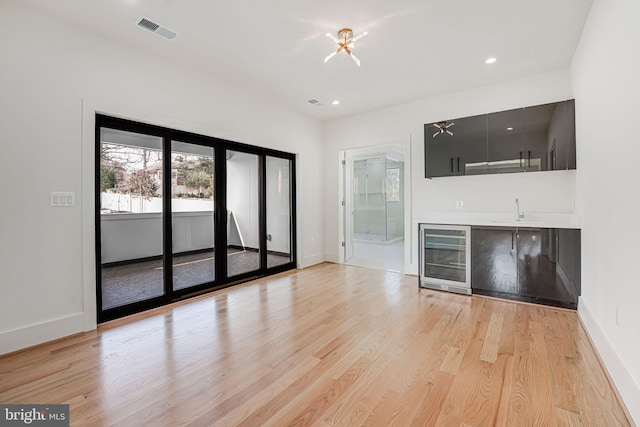 interior space featuring beverage cooler, sink, and light wood-type flooring