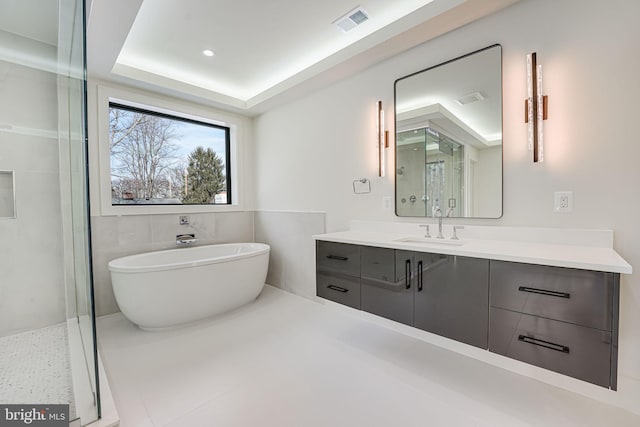 bathroom with vanity, a tray ceiling, and plus walk in shower