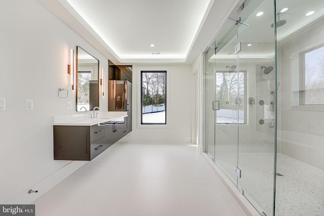 bathroom featuring walk in shower, vanity, and a raised ceiling