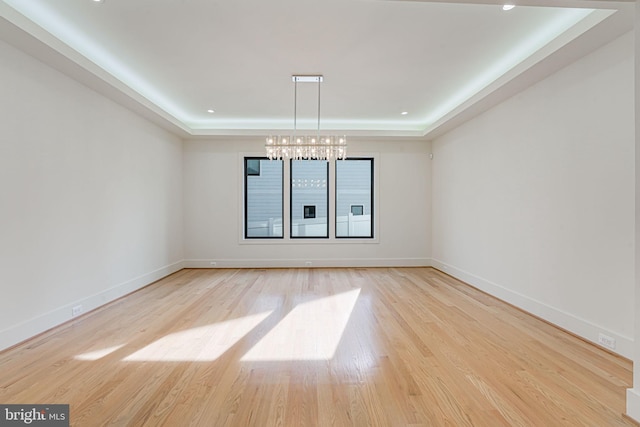 interior space featuring a notable chandelier, a tray ceiling, and light hardwood / wood-style flooring