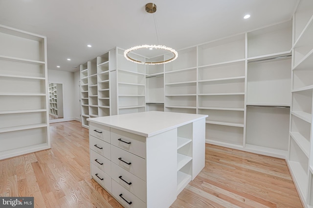 walk in closet featuring a notable chandelier and light wood-type flooring