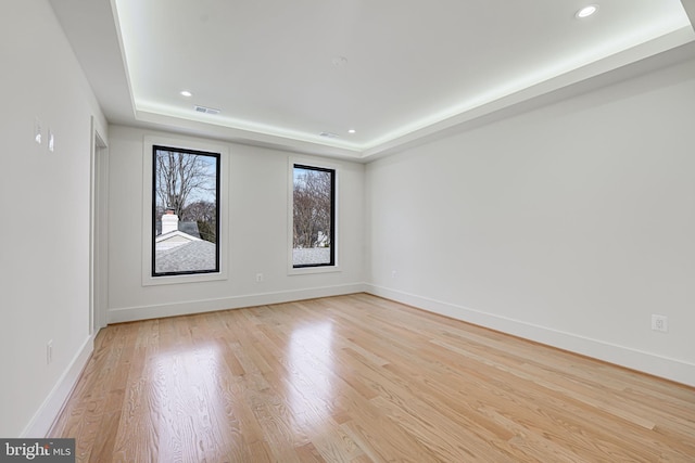 unfurnished room with a tray ceiling and light hardwood / wood-style floors