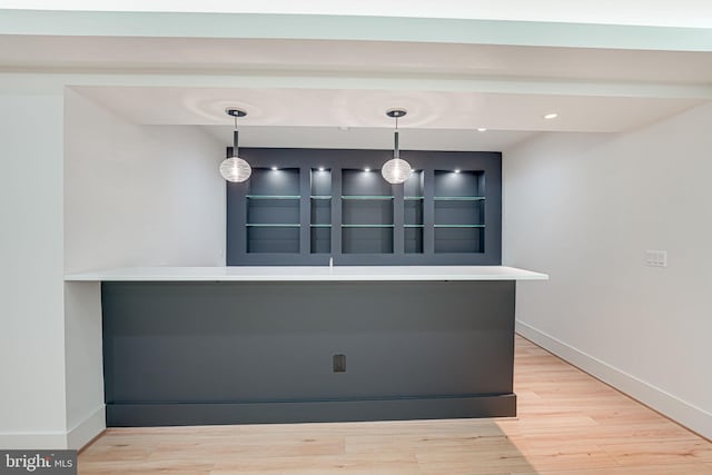 bar with hanging light fixtures and light hardwood / wood-style flooring