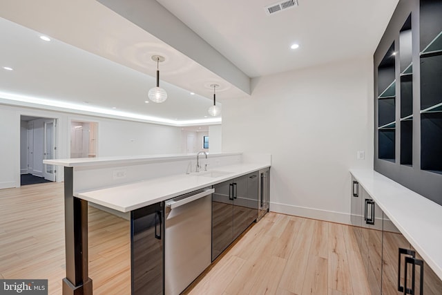 kitchen featuring a breakfast bar area, hanging light fixtures, light hardwood / wood-style flooring, stainless steel dishwasher, and kitchen peninsula