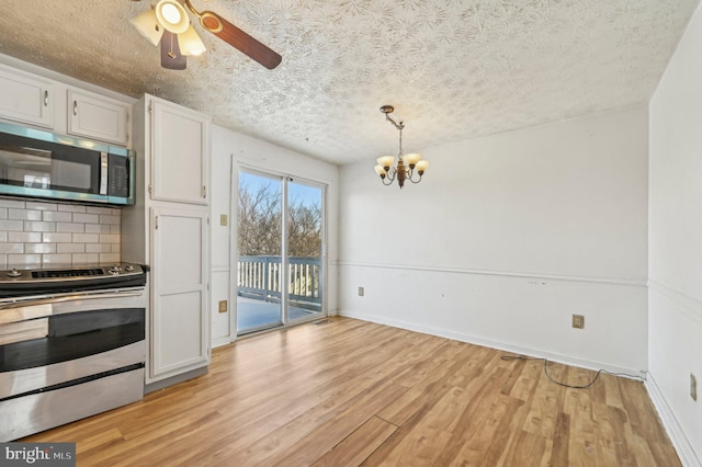 kitchen with appliances with stainless steel finishes, white cabinets, backsplash, and decorative light fixtures