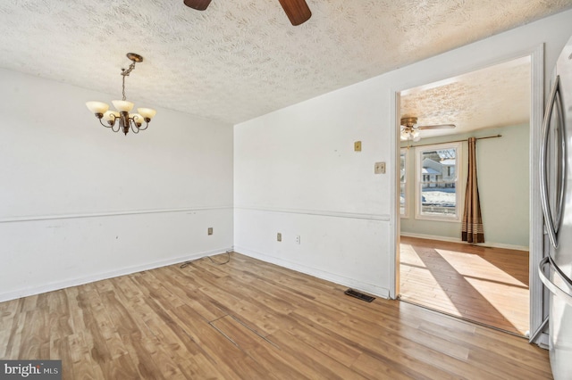 unfurnished room with a notable chandelier, a textured ceiling, and wood-type flooring