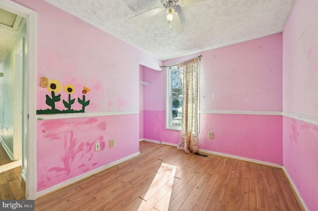 spare room with a textured ceiling, ceiling fan, and light wood-type flooring