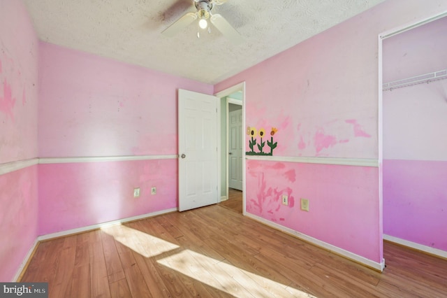 unfurnished bedroom featuring hardwood / wood-style floors, a closet, ceiling fan, and a textured ceiling