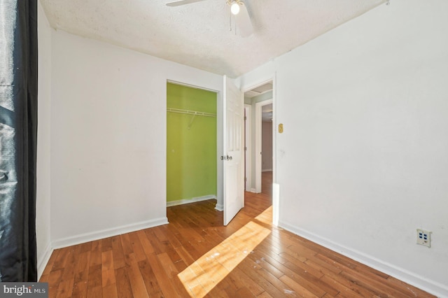 unfurnished bedroom featuring wood-type flooring, a closet, ceiling fan, and a textured ceiling