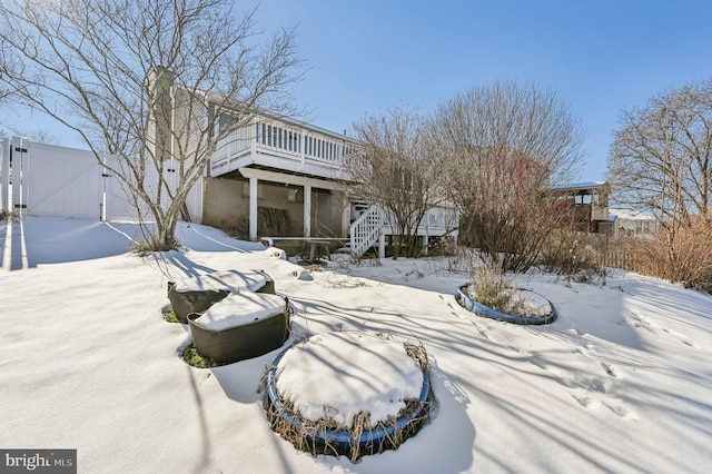 snow covered back of property featuring a wooden deck