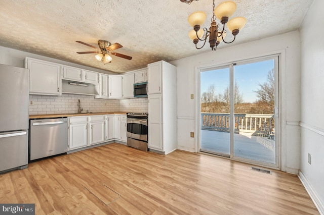 kitchen featuring tasteful backsplash, appliances with stainless steel finishes, pendant lighting, white cabinets, and sink