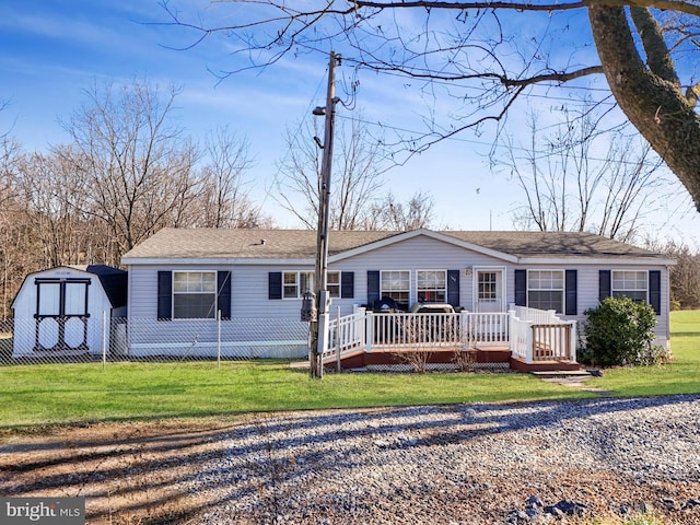 ranch-style home with a front yard, a shed, and a wooden deck