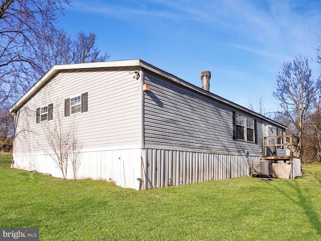 view of side of property with a yard and central AC