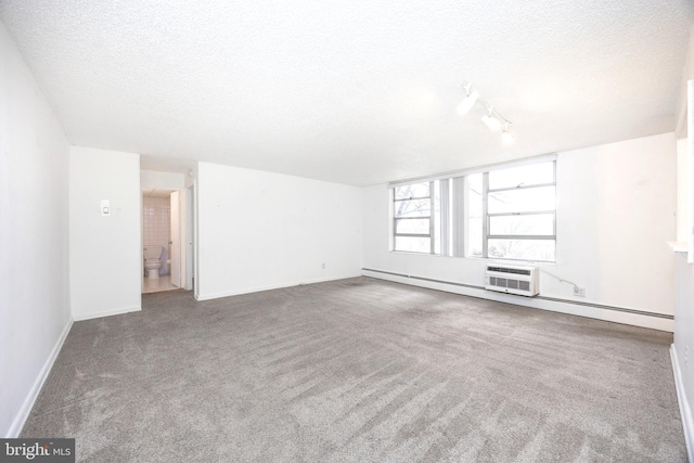 carpeted spare room featuring a textured ceiling, track lighting, and a baseboard heating unit