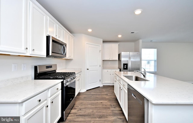 kitchen featuring stainless steel appliances, white cabinetry, a center island with sink, and sink