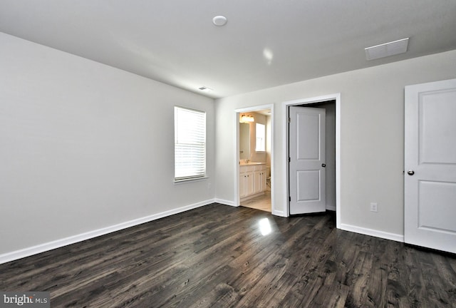 unfurnished bedroom featuring connected bathroom and dark hardwood / wood-style floors