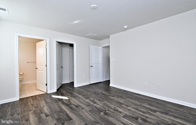 unfurnished bedroom with dark hardwood / wood-style flooring and connected bathroom