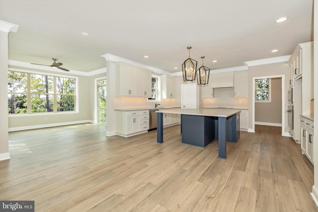 kitchen featuring a center island, appliances with stainless steel finishes, pendant lighting, white cabinets, and custom exhaust hood