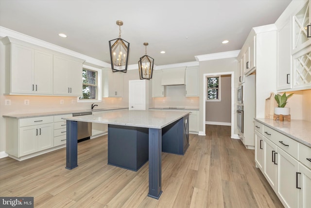 kitchen with custom exhaust hood, a breakfast bar, hanging light fixtures, light hardwood / wood-style floors, and a kitchen island