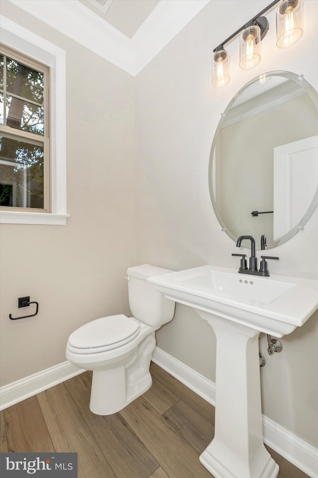 bathroom featuring wood-type flooring, toilet, and ornamental molding