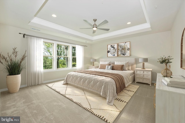 bedroom with light carpet, a tray ceiling, and ceiling fan