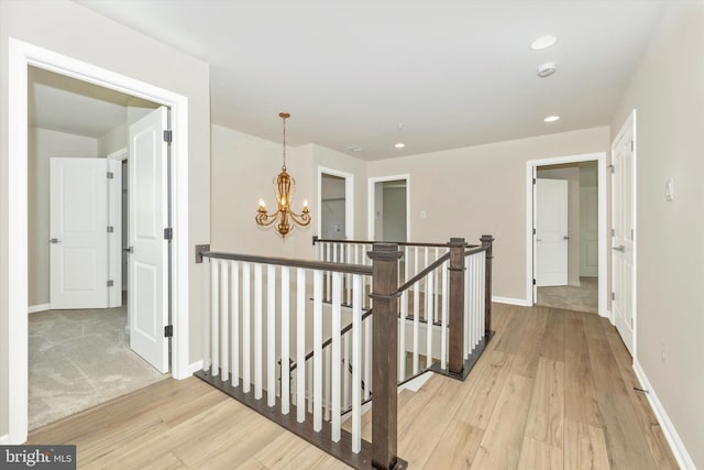 hallway featuring an inviting chandelier and light hardwood / wood-style flooring