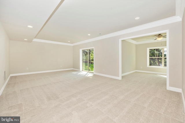 spare room with ceiling fan, crown molding, and light carpet