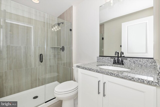 bathroom featuring vanity, toilet, and a shower with door