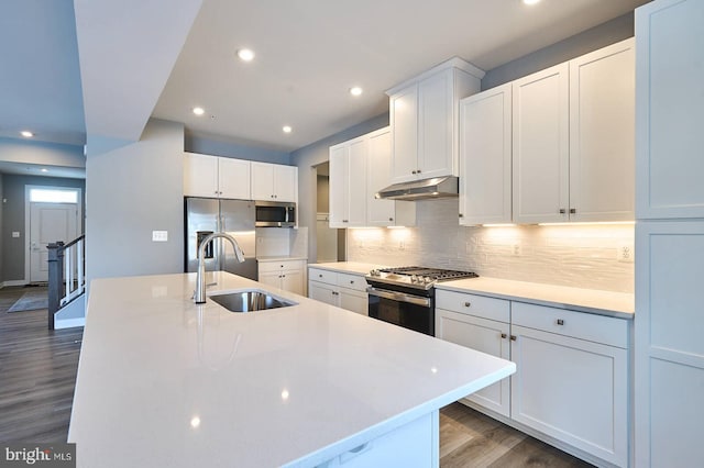 kitchen featuring dark hardwood / wood-style floors, stainless steel appliances, a center island with sink, white cabinetry, and sink