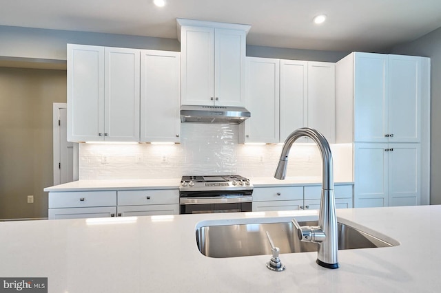 kitchen featuring white cabinets, stainless steel gas stove, backsplash, and sink