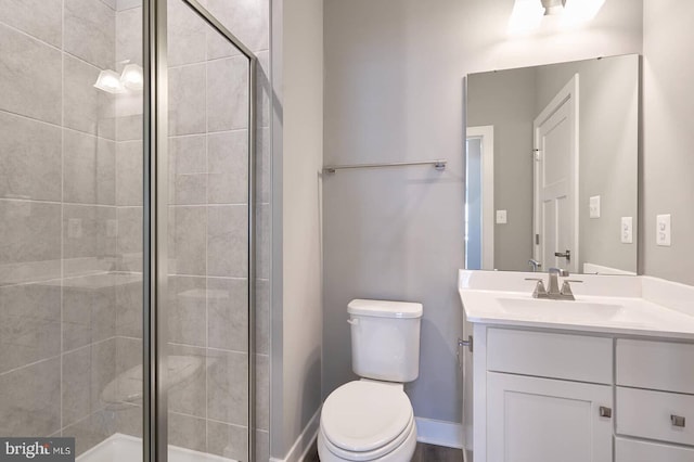 bathroom featuring toilet, a shower with door, and vanity