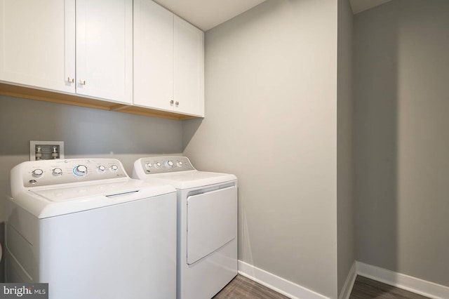 laundry area featuring dark hardwood / wood-style flooring, washing machine and clothes dryer, and cabinets