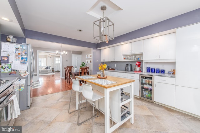 kitchen with appliances with stainless steel finishes, white cabinetry, hanging light fixtures, and wine cooler