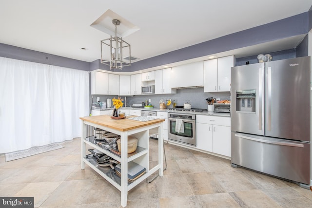 kitchen featuring backsplash, custom exhaust hood, stainless steel appliances, pendant lighting, and white cabinets