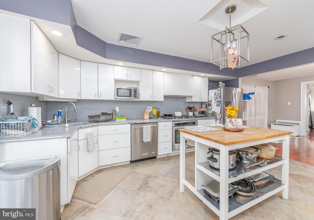 kitchen featuring decorative backsplash, appliances with stainless steel finishes, sink, decorative light fixtures, and white cabinetry