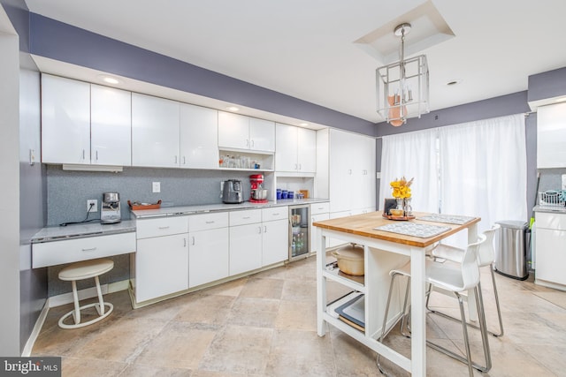 kitchen featuring white cabinets, hanging light fixtures, wine cooler, decorative backsplash, and a breakfast bar area