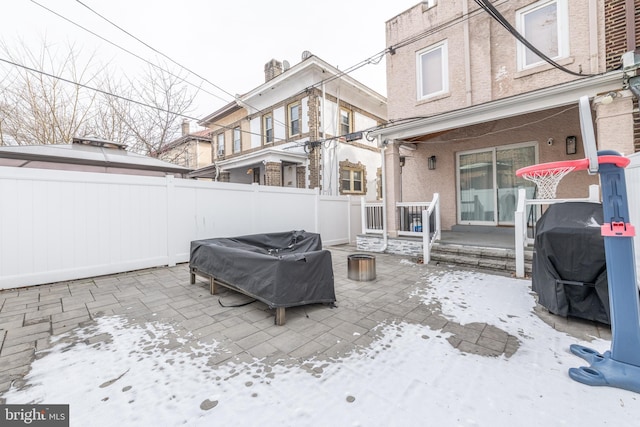 snow covered patio featuring grilling area and an outdoor fire pit