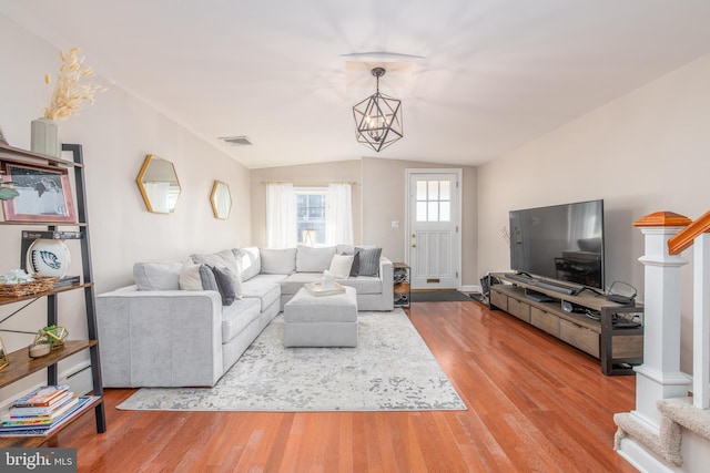 living room featuring hardwood / wood-style floors, a chandelier, and lofted ceiling