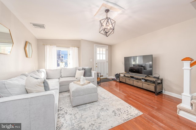 living room with hardwood / wood-style floors, lofted ceiling, and an inviting chandelier