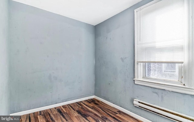 unfurnished room featuring a baseboard heating unit and dark wood-type flooring