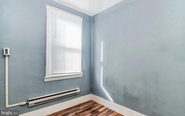 empty room featuring hardwood / wood-style flooring and a baseboard radiator