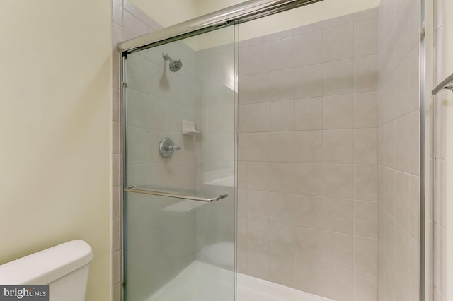 bathroom featuring toilet and a shower with door