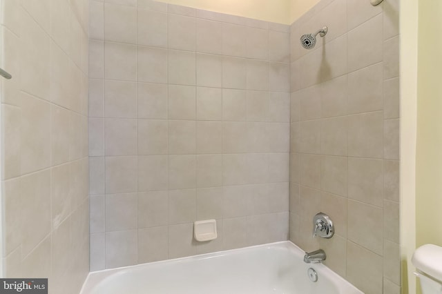 bathroom with toilet and tiled shower / bath